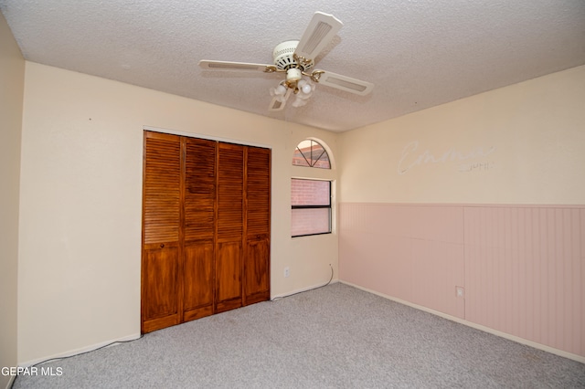 unfurnished bedroom featuring a textured ceiling, light carpet, ceiling fan, and a closet