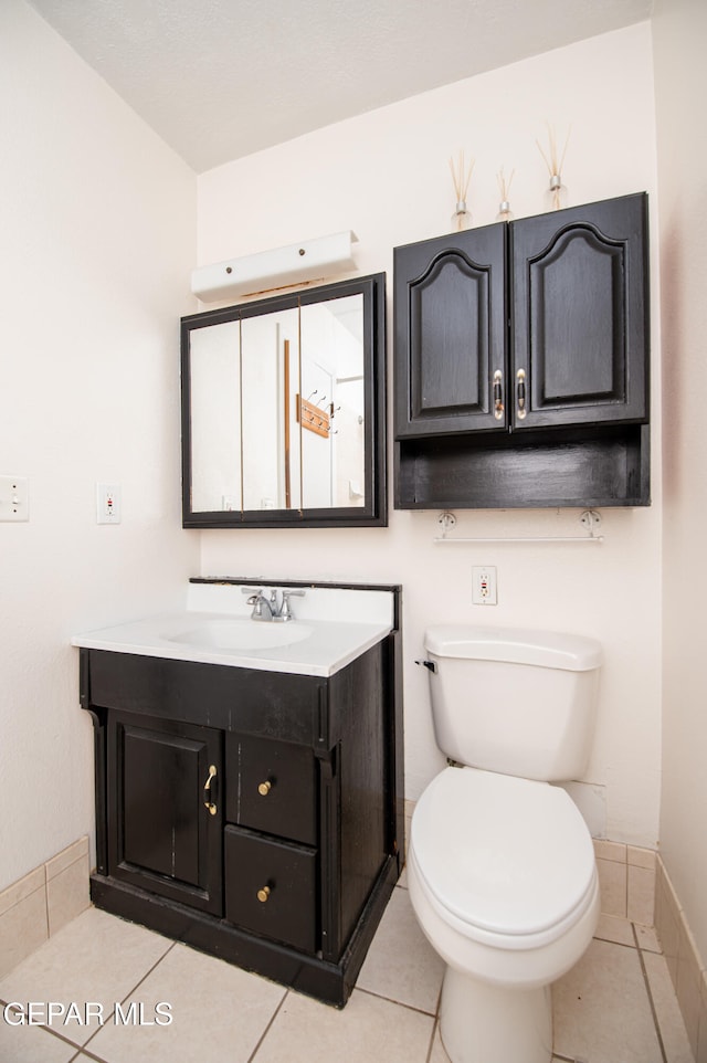 bathroom with toilet, vanity, and tile patterned floors