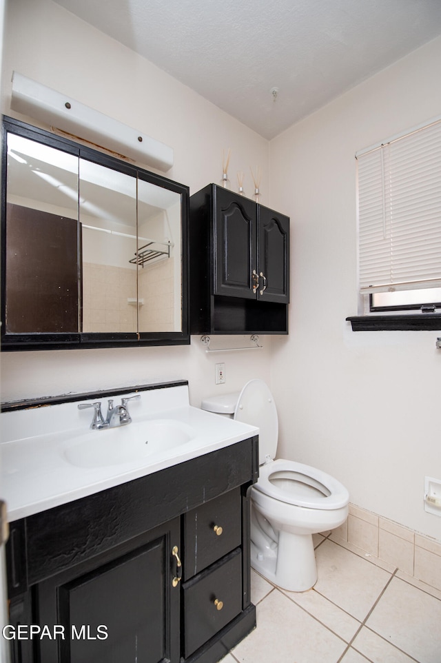 bathroom featuring toilet, vanity, tile patterned floors, and walk in shower