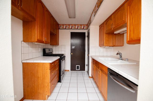 kitchen featuring tile counters, black range oven, stainless steel dishwasher, and sink