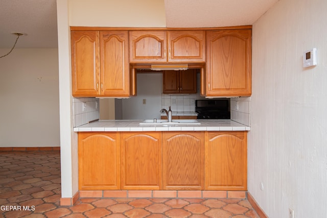 kitchen with tile counters, sink, and backsplash