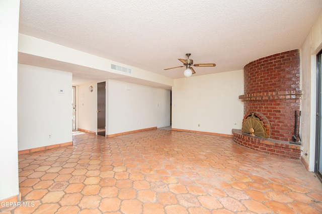 unfurnished living room featuring a fireplace, ceiling fan, and a textured ceiling