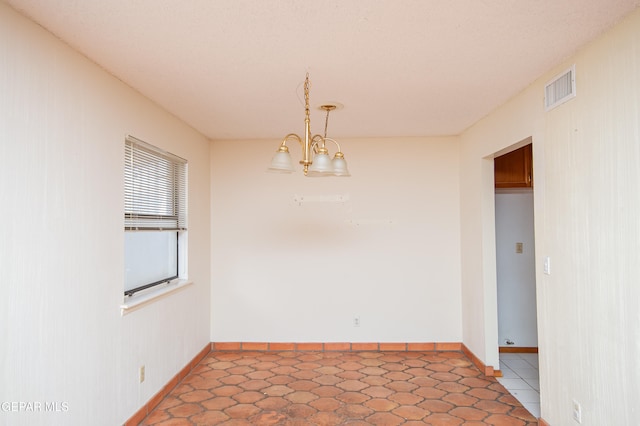 tiled empty room featuring a chandelier