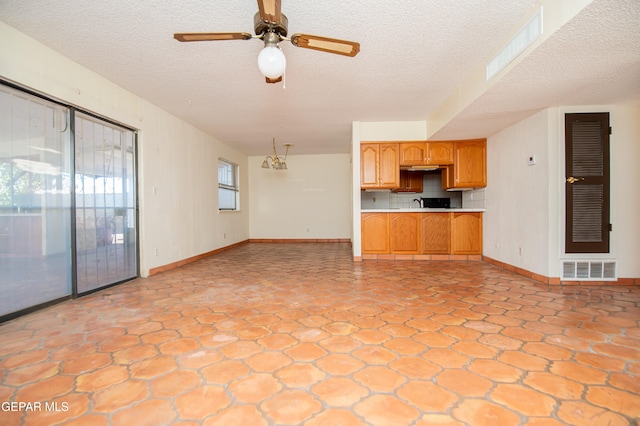 unfurnished living room featuring a textured ceiling and ceiling fan