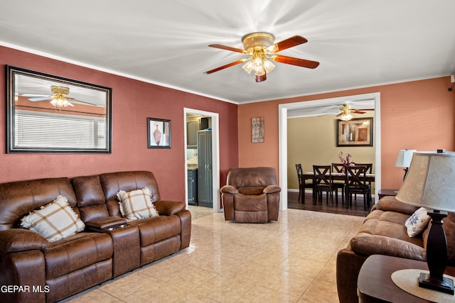 living room with ornamental molding, a ceiling fan, and light tile patterned flooring