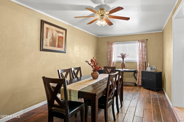 dining space with ceiling fan, ornamental molding, dark wood finished floors, and baseboards