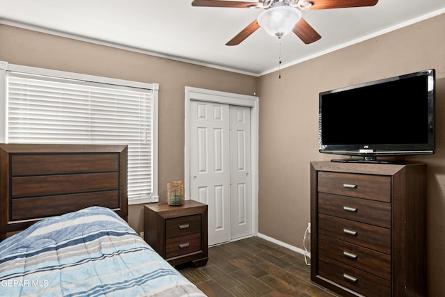 bedroom featuring dark wood-style flooring, a ceiling fan, baseboards, a closet, and crown molding