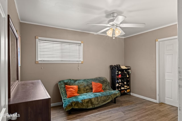 living area featuring baseboards, ornamental molding, ceiling fan, and wood finished floors