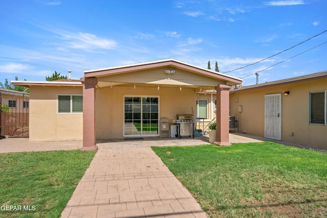 back of house featuring stucco siding, fence, a lawn, and a patio