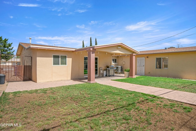 rear view of property featuring a patio, a lawn, fence, and stucco siding