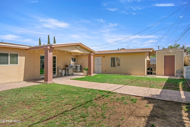 back of house with a patio area, a yard, and a storage unit