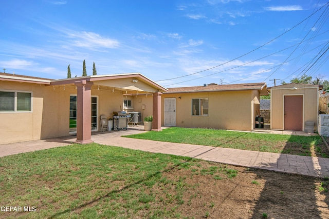 rear view of property with an outbuilding, a patio, a shed, and stucco siding