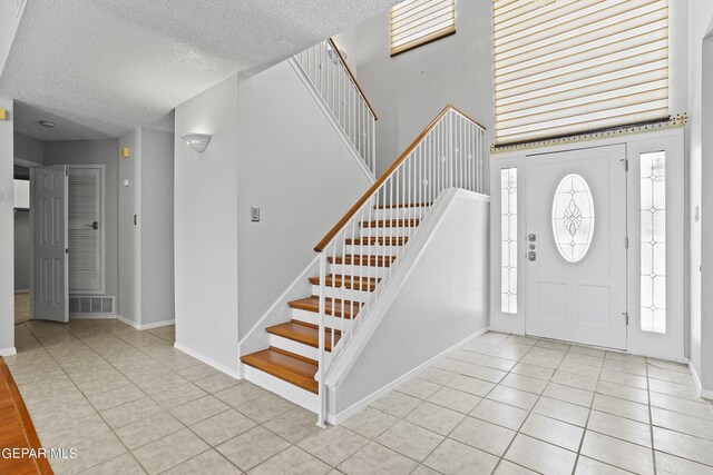 foyer entrance with light tile patterned floors, a wealth of natural light, and a textured ceiling