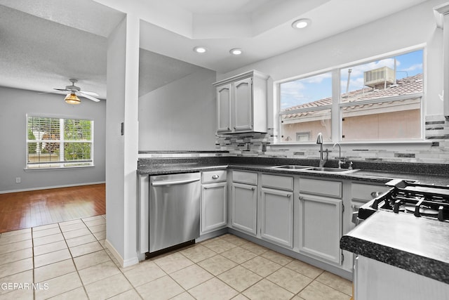 kitchen with light tile patterned floors, gray cabinets, ceiling fan, dishwasher, and sink