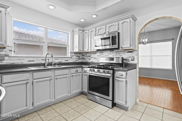 kitchen with light tile patterned floors, stainless steel appliances, backsplash, and sink