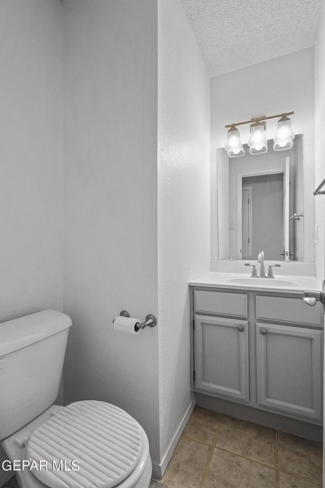 bathroom featuring a textured ceiling, toilet, and vanity