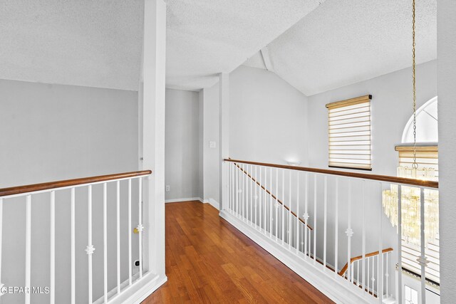 hallway featuring lofted ceiling, a textured ceiling, and hardwood / wood-style floors