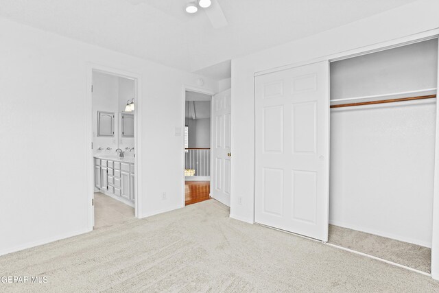 unfurnished bedroom featuring ceiling fan, light colored carpet, a closet, and connected bathroom