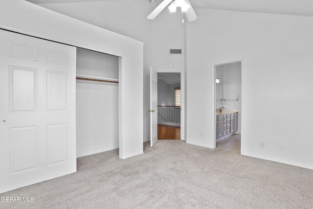 unfurnished bedroom with ensuite bathroom, light colored carpet, ceiling fan, high vaulted ceiling, and a closet