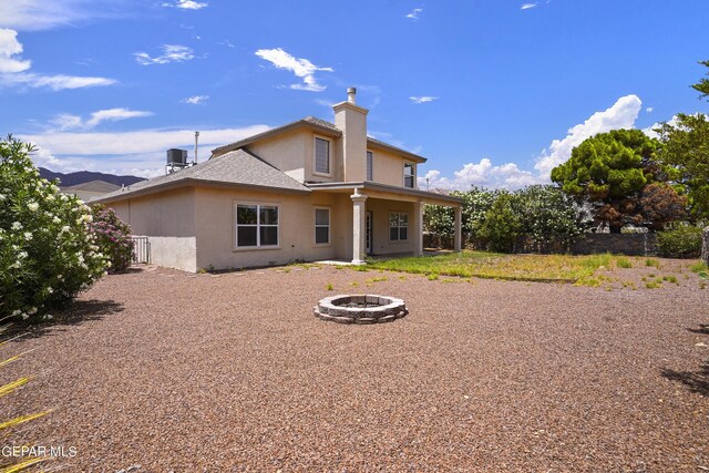 back of property with an outdoor fire pit and central AC unit