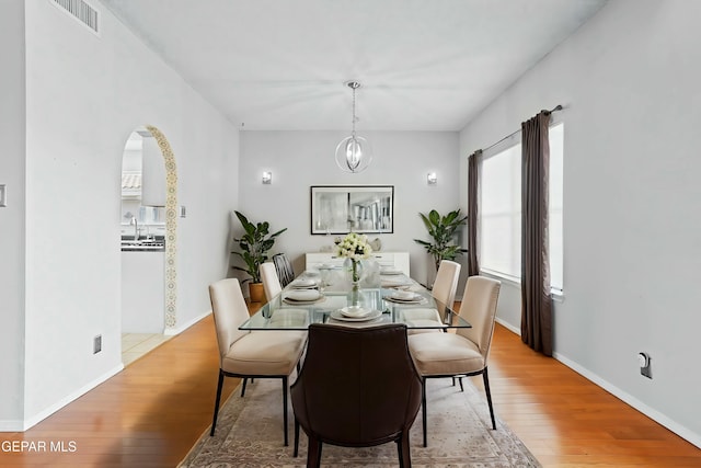 dining area with sink, a notable chandelier, and light wood-type flooring