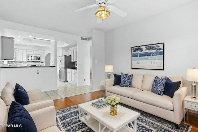 living room featuring ceiling fan, light tile patterned floors, and sink