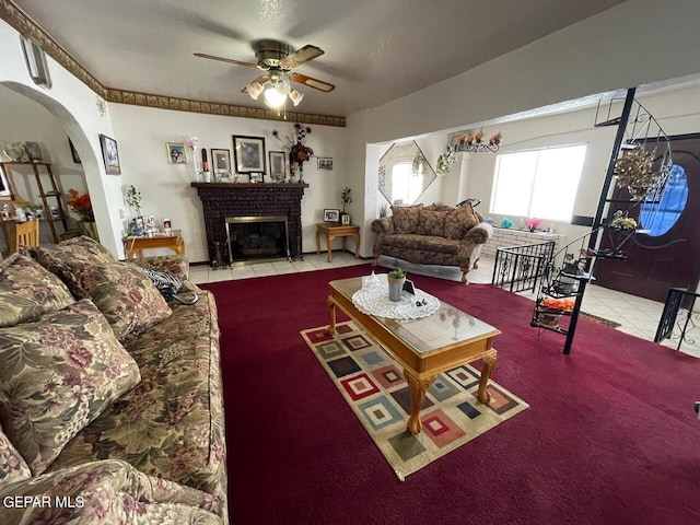 carpeted living room with a brick fireplace and ceiling fan