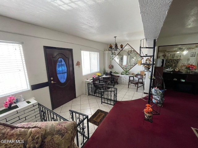 tiled entrance foyer featuring a chandelier and a textured ceiling