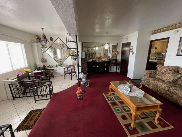 living room with an inviting chandelier, a textured ceiling, and light tile patterned flooring