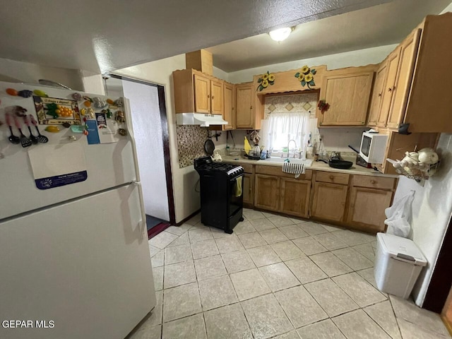 kitchen featuring gas stove, white refrigerator, sink, and light tile patterned floors