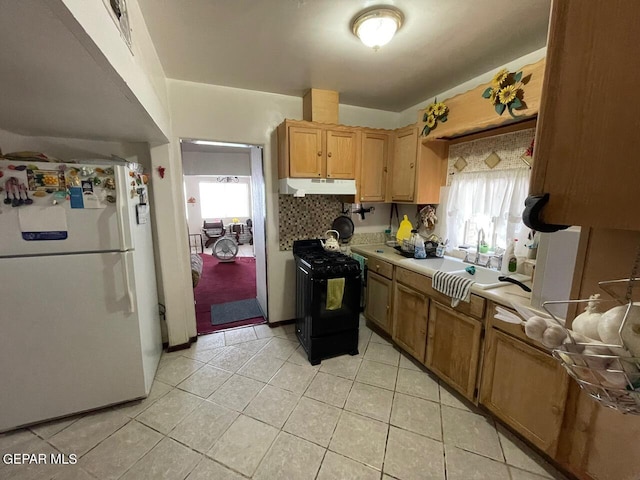 kitchen featuring white refrigerator, sink, backsplash, light tile patterned floors, and black gas range