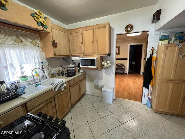 kitchen with black range oven, sink, and light wood-type flooring