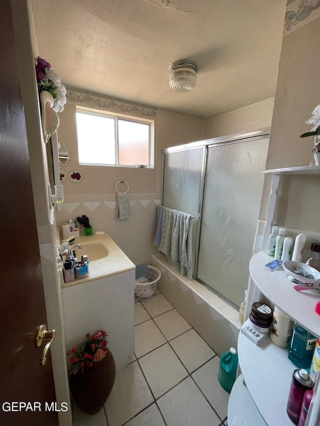 bathroom featuring a shower with shower door, vanity, tile patterned flooring, and a textured ceiling