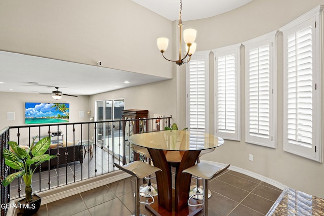 dining space with ceiling fan with notable chandelier and dark tile patterned flooring