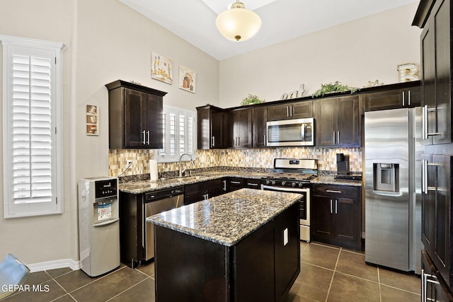 kitchen with tasteful backsplash, stainless steel appliances, dark tile patterned flooring, and a kitchen island