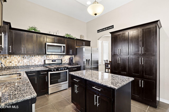 kitchen featuring light stone counters, stainless steel appliances, sink, and a kitchen island