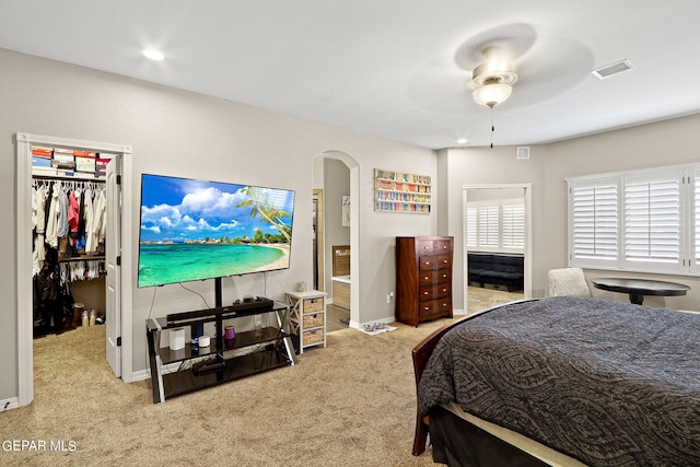 bedroom featuring light carpet, a spacious closet, a closet, and ceiling fan