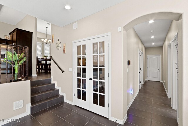 hall featuring an inviting chandelier and dark tile patterned floors