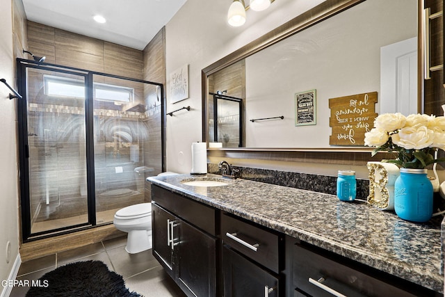 bathroom with vanity, a shower with shower door, tile patterned floors, and toilet