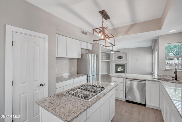 kitchen featuring pendant lighting, white cabinets, light hardwood / wood-style floors, sink, and stainless steel appliances