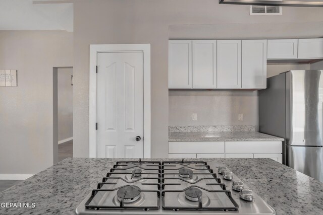 kitchen featuring hardwood / wood-style flooring, white cabinetry, light stone countertops, and stainless steel appliances