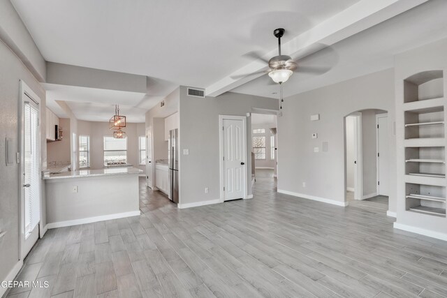 unfurnished living room with ceiling fan, light hardwood / wood-style floors, and built in features