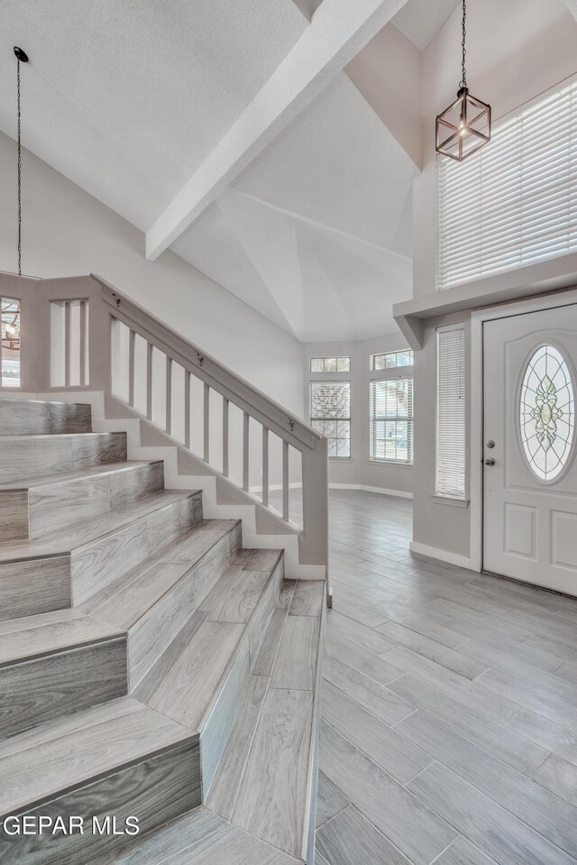 entryway with a notable chandelier, high vaulted ceiling, and light hardwood / wood-style floors