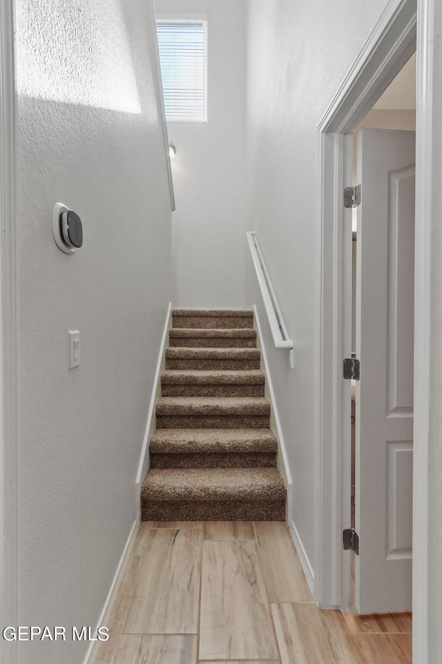 staircase featuring baseboards and wood finished floors