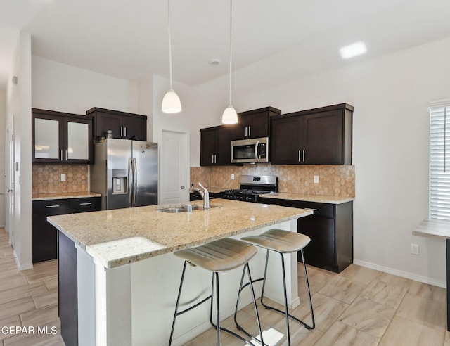 kitchen with a breakfast bar area, an island with sink, stainless steel appliances, sink, and decorative backsplash