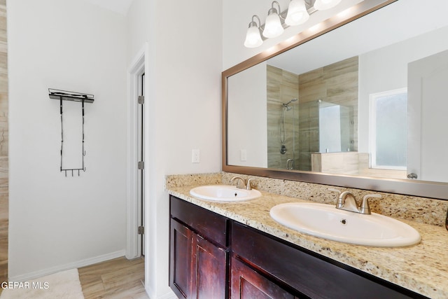 bathroom featuring double vanity, wood finished floors, a stall shower, and a sink