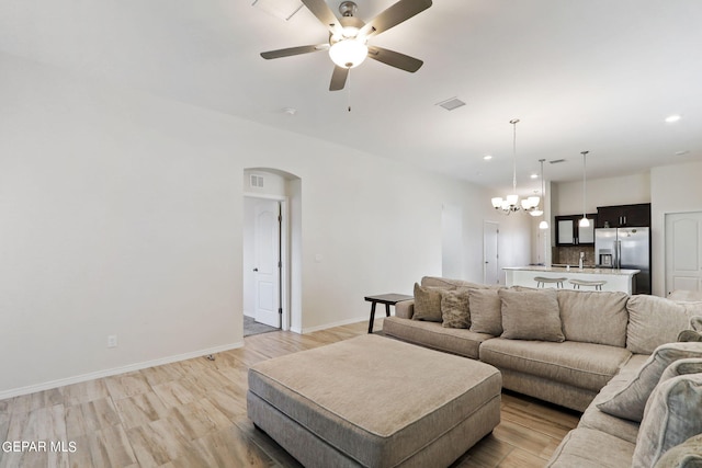 living room with ceiling fan with notable chandelier, sink, and light hardwood / wood-style flooring