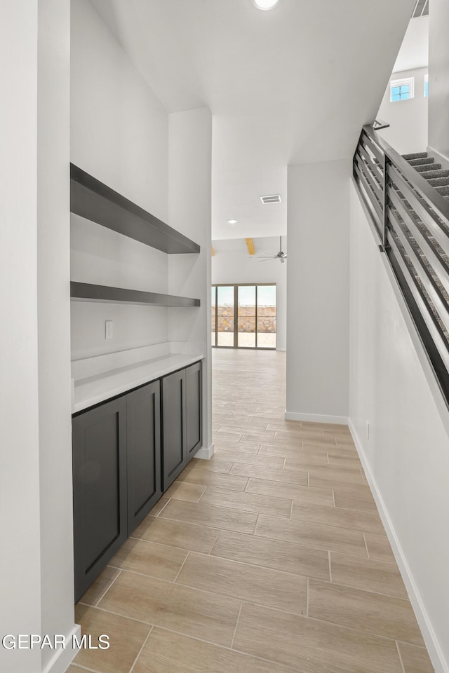 corridor featuring wood tiled floor, visible vents, stairway, and baseboards