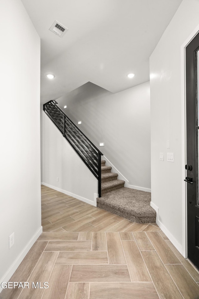 stairs with recessed lighting, visible vents, baseboards, and parquet flooring