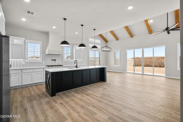 kitchen featuring open floor plan, premium range hood, visible vents, and decorative backsplash